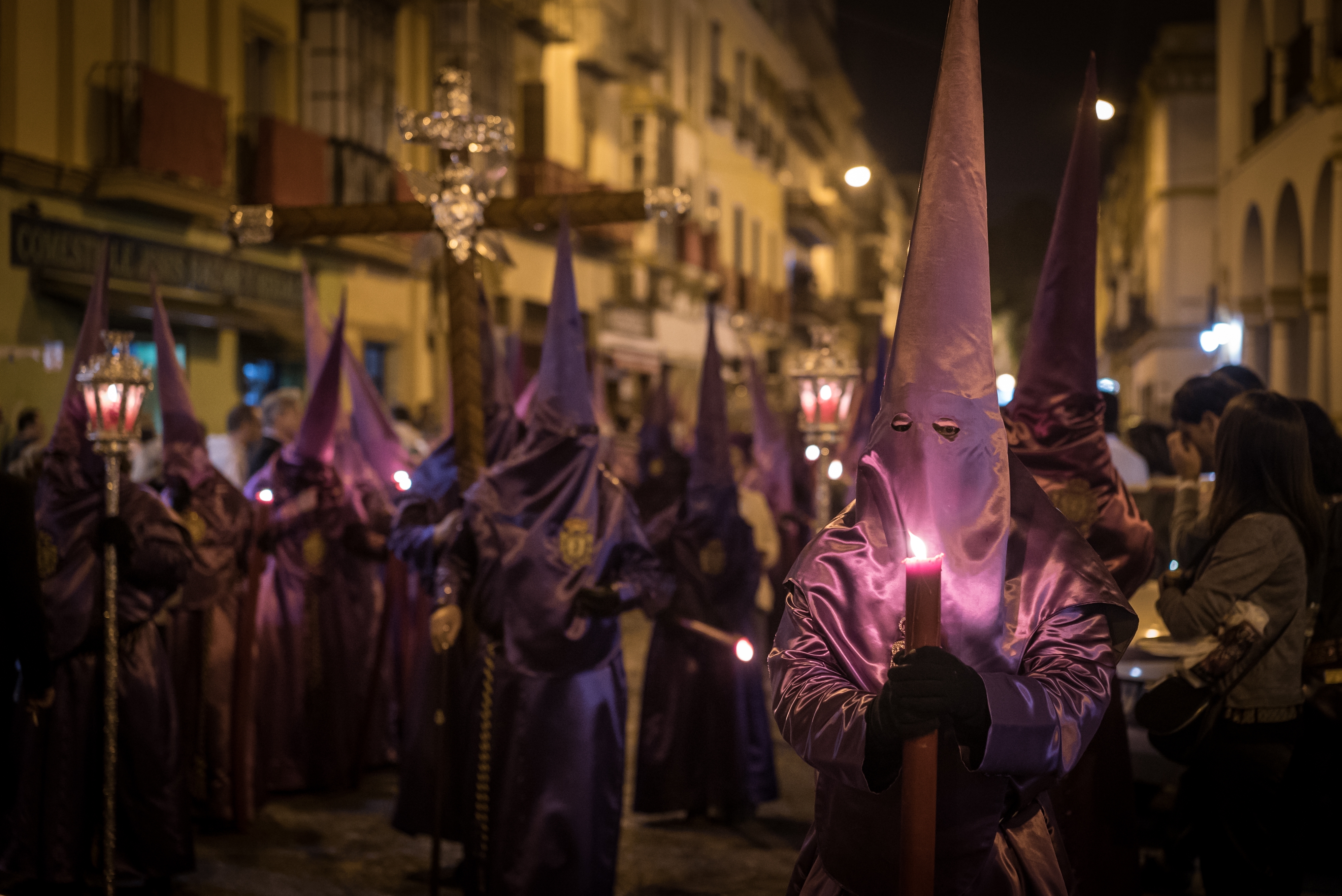 Semana Santa procession in Seville at night with candlelit nazarenos